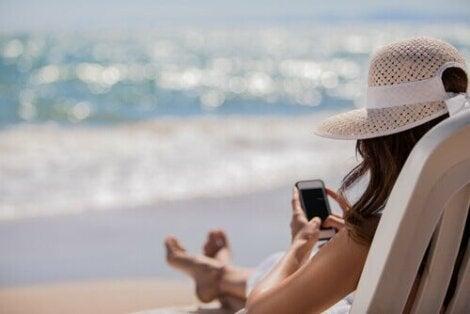 Mujer en la playa con su teléfono 470x314